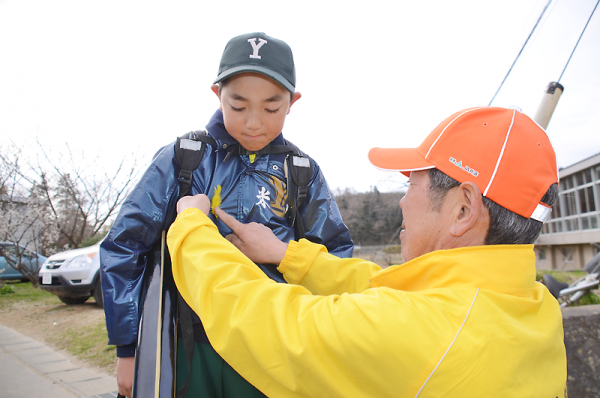黄色い羽根をつけてもらい、交通安全意識を高める児童=米崎小学校